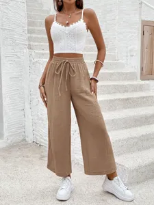 Detailed view of the casual wide-leg trousers paired with white top on stone stairs.