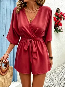 Elegant V-neck solid color short romper with waist tie in a scenic outdoor setting, detail view.
