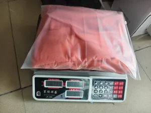 Detailed view showing the packaged knitwear weighed on a digital scale in warehouse.