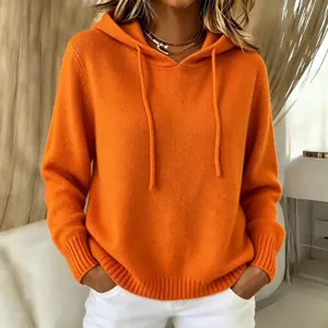 Close-up detail of a vibrant orange knit hoodie featuring a cozy hood and matching drawstrings.
