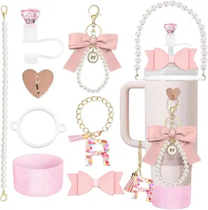 Vista dettagliata del set di accessori per tazza rosa con fiocco e ciondoli di perle.