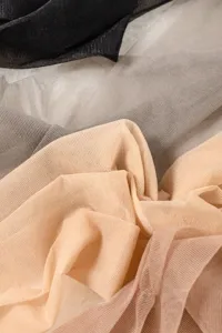 Gros plan détaillé de tissu de bas transparent, montrant texture lisse et multiples couleurs.
