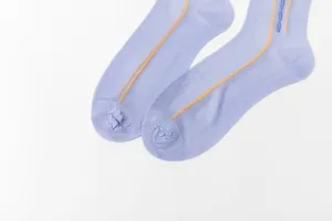 Close-up of light purple thin nylon socks with decorative yellow and blue vertical stitch lines.