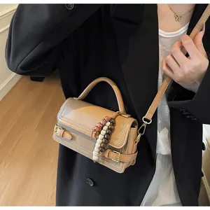 Detail view of the trendy chic crossbody bag with bead charms and elegant top handle.