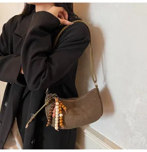 Detailaufnahme einer retro braunen Wildleder Achseltasche mit Holzperlen Anhänger.