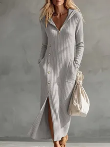 Vista dettagliata dell'abito in maglia grigio con cappuccio, zip anteriore e bottoni stilosi.