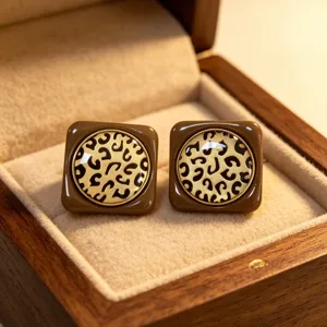 Primer plano detallado de pendientes de tuerca cuadrados marrones con estampado de leopardo.