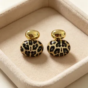 Primer plano detalle de pendientes retro metal estampado leopardo en bandeja beige.