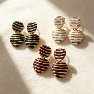 Close-up detail of retro striped enamel round and heart stud earrings, elegant vintage design.