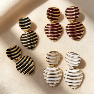 Close-up detail shot of vintage striped enamel earrings with gold and geometric contrast design.