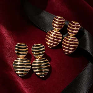 Vintage striped enamel earrings close-up, French style gold and black jewelry detail.
