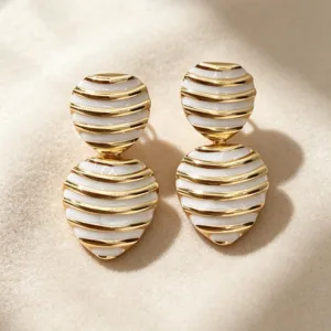 Vintage striped heart enamel earrings detail view, elegant gold and white jewelry closeup.