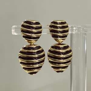 Detail close-up of vintage striped heart enamel drop earrings with gold-tone metal trim.