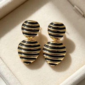 Close-up view of vintage gold and black striped heart stud earrings, elegant metallic texture.