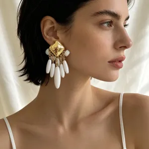 Gros plan détail de boucles d'oreilles pendantes carrées dorées texturées vintage.
