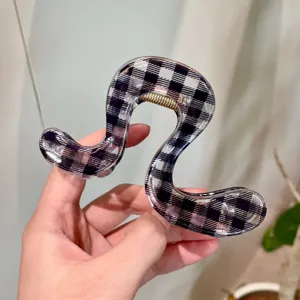 Primo piano dell'esclusiva molletta per capelli irregolare con un motivo a quadri bianco e nero.