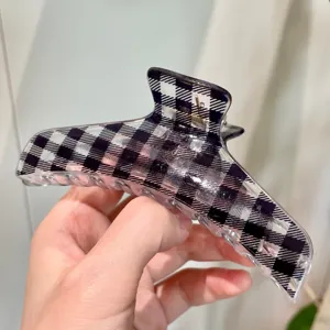 Primo piano dettagliato di un'elegante molletta per capelli a quadri neri e bianchi, trasparente.
