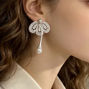 Vue détaillée de boucles d'oreilles pendantes élégantes en dentelle avec perles.