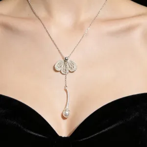 Vue détaillée d'un collier pendentif en dentelle argentée avec perle sur une robe.