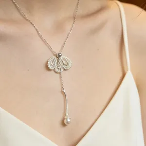 Collier pendentif fleur en dentelle filigrane argentée avec détail de perle élégant.
