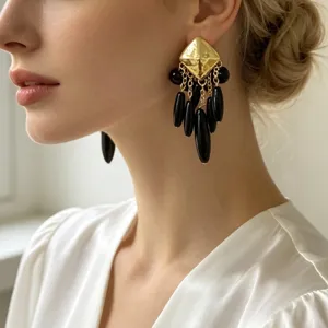 Dessus géométrique plaqué or avec boucles d'oreilles pendantes cascade noires gros plan.