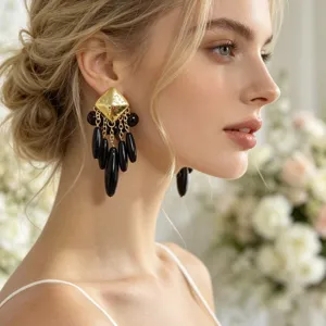 Gros plan détail de boucles d'oreilles pendantes style vintage texturées or et perles noires.