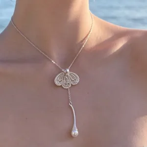 Gros plan détaillé sur le collier pendentif pétale de dentelle argentée et perle suspendue.