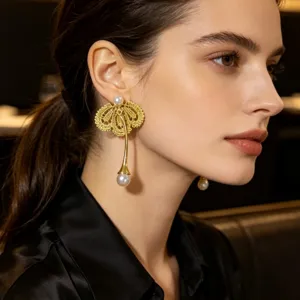 Boucles d'oreilles pendantes en dentelle et perles dorées, design élégant pour un look chic.