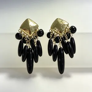 Gros plan des boucles d'oreilles vintage carré or et pampilles de perles noires détail.