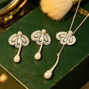 Gros plan détaillé de boucles d'oreilles perles en dentelle et collier pendentif assorti.