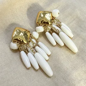 Gros plan sur les boucles doreilles pendantes dores et perles blanches style vintage chic