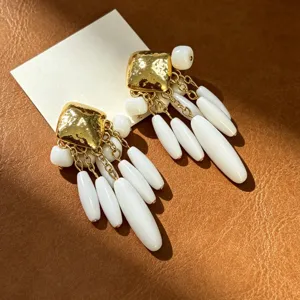 Gros plan détaillé de boucles d'oreilles vintage dorées texturées en forme de larme.