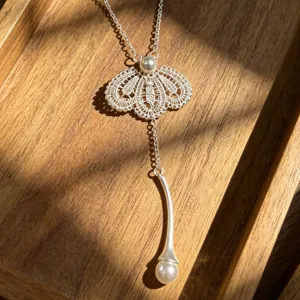 Élégant collier pendentif Y en dentelle argentée et perles avec design creux délicat.