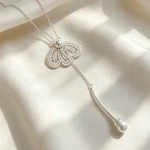 Élégante cravatte en argent avec perle et pendentif floral en dentelle creuse, bijou raffiné de cou.