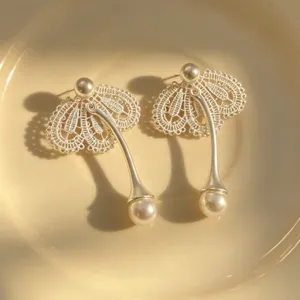 Vue détaillée de boucles d'oreilles perles en dentelle élégantes avec pendentif en métal.