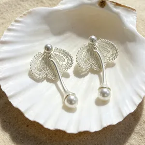 Gros plan détaillé de boucles d'oreilles nacrées en dentelle argentée dans un beau coquillage blanc.