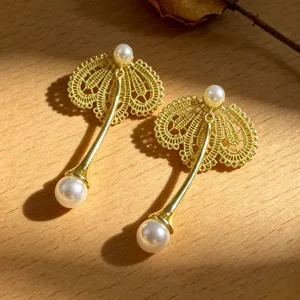 Boucles d'oreilles pendantes en dentelle dorée et perles élégantes pour un look chic et raffiné.