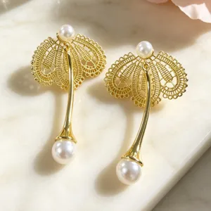 Gros plan détaillé de boucles d'oreilles pendantes en perles de dentelle dorée sur marbre.