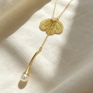 Élégant collier Y doré avec pendentif en dentelle délicate et perles brillantes pour femmes.