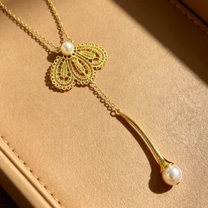 Gros plan détaillé de l'élégant collier cravate en dentelle dorée et perles nacrées.