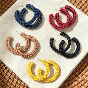 Gedetailleerde opname van kleurrijke gevlochten leertextuur C-oorringen, modieuze sieraden.