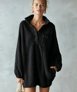 Close-up detail of the black fleece pullover dress showing the stand collar and pocket texture.