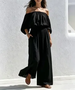Details of the black off-shoulder wide-leg jumpsuit, featuring loose fit and clean outdoor scene.