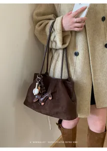 Brown suede shoulder bag detail featuring cute dachshund charm and minimalist retro aesthetic.