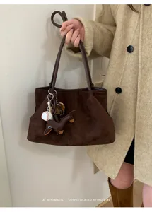 Brown suede handbag detail shot showcasing retro shoulder straps and cute charm accessories