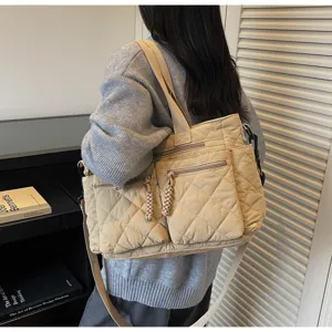 Vista detallada del bolso acolchado beige que muestra múltiples bolsillos con cremallera y tela.