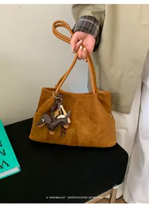 Detailed view of brown suede tote bag with cute dachshund keychain, stylish retro commute handbag.