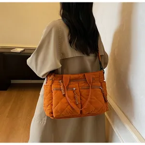 Vista detallada del bolso de hombro acolchado naranja con múltiples bolsillos y textura.