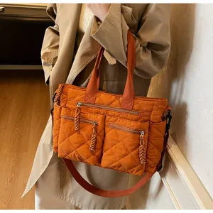 Primer plano detallado del bolso tote acolchado naranja con asas dobles y bolsillos.