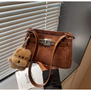 Brown suede retro shoulder bag with metal lock and cute plush dog charm for women chic daily.